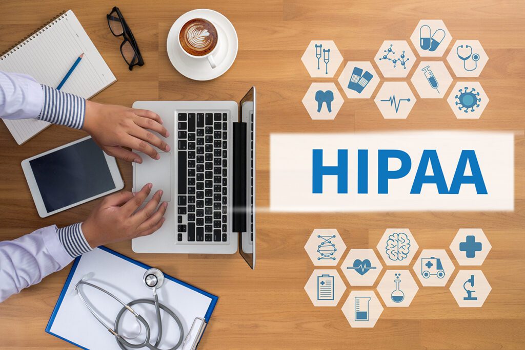 A person typing on a laptop with an image overlay of the word “HIPAA.”