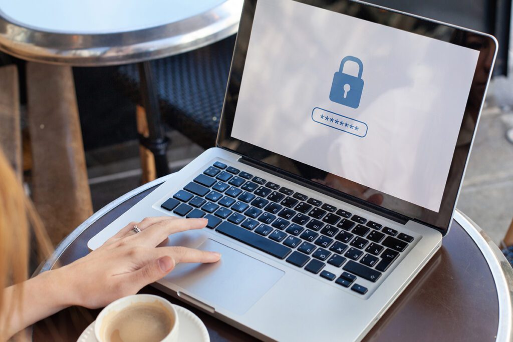A woman entering her password at a laptop in public