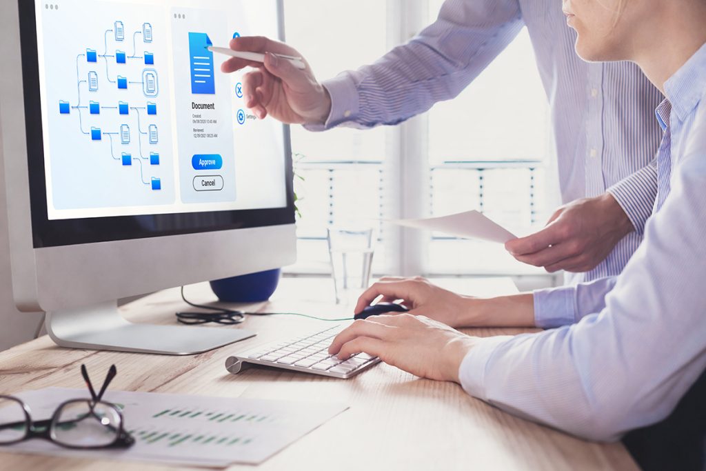 Two coworkers examine a data structure on their desktop as they discuss their strategy