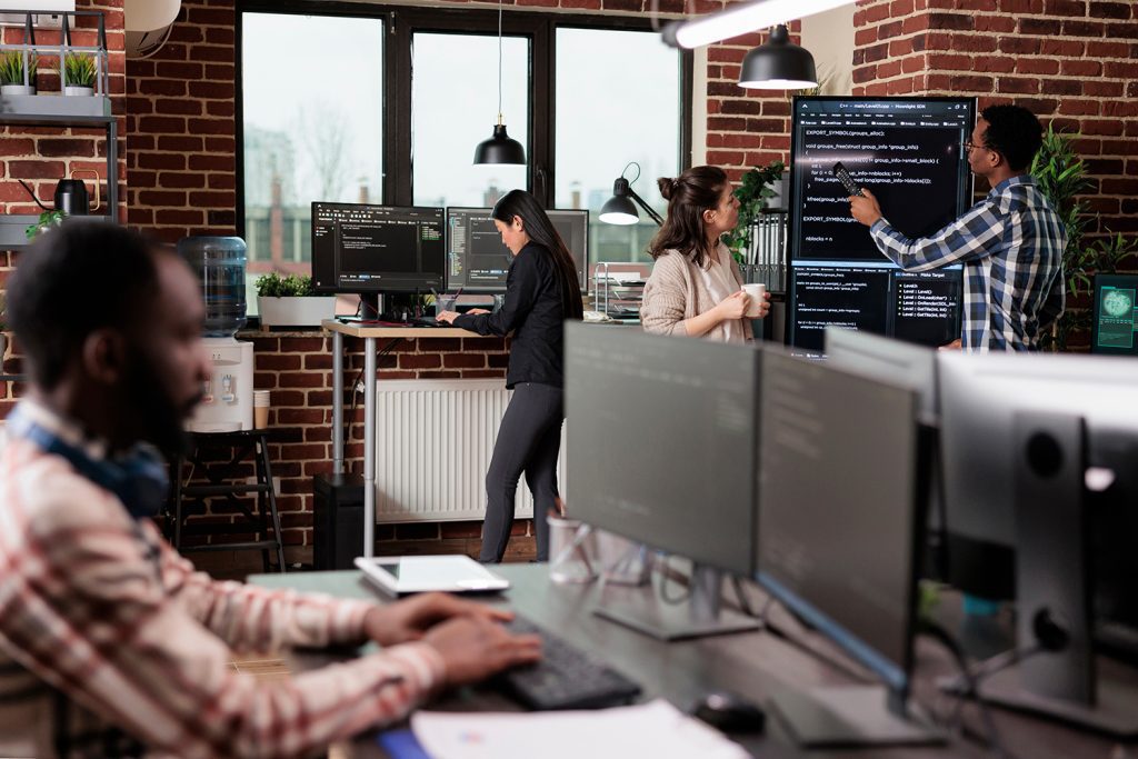 A group of 4 IT professionals work at their own screens.