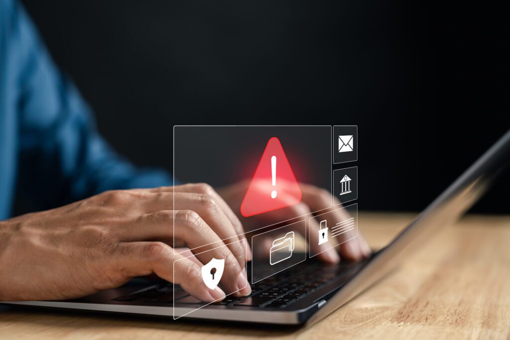 a man typing on a laptop with a warning message on the screen